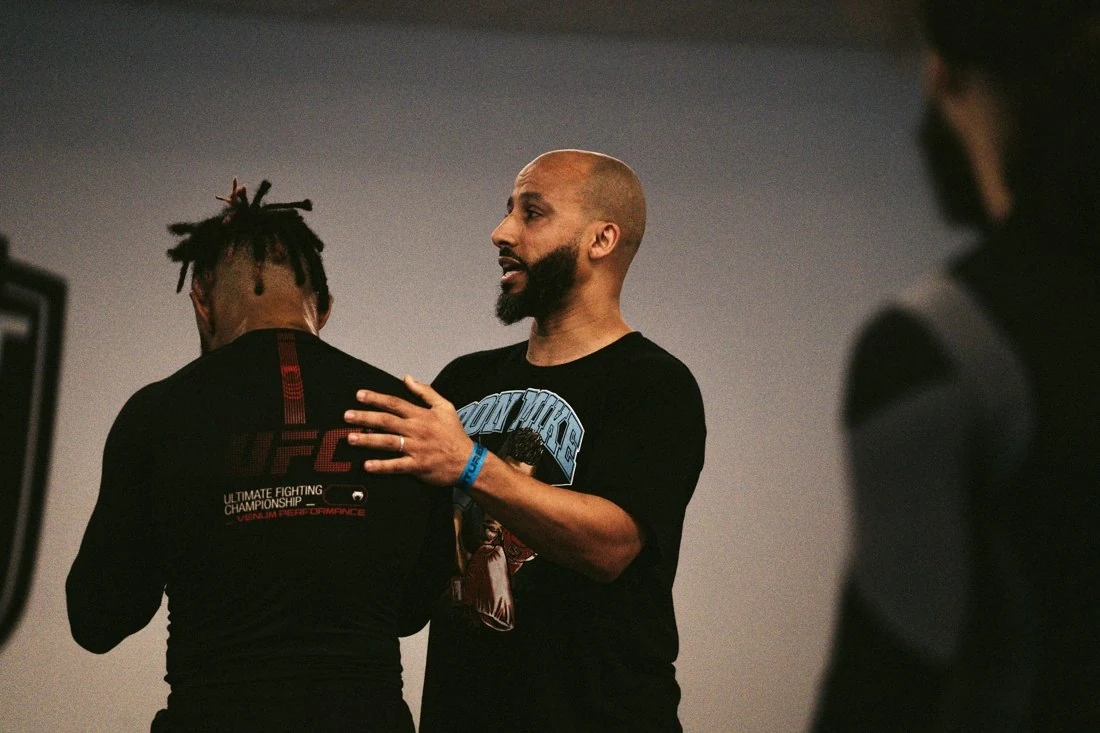 Deux personnes échangent un conseil technique pendant une séance de boxe.