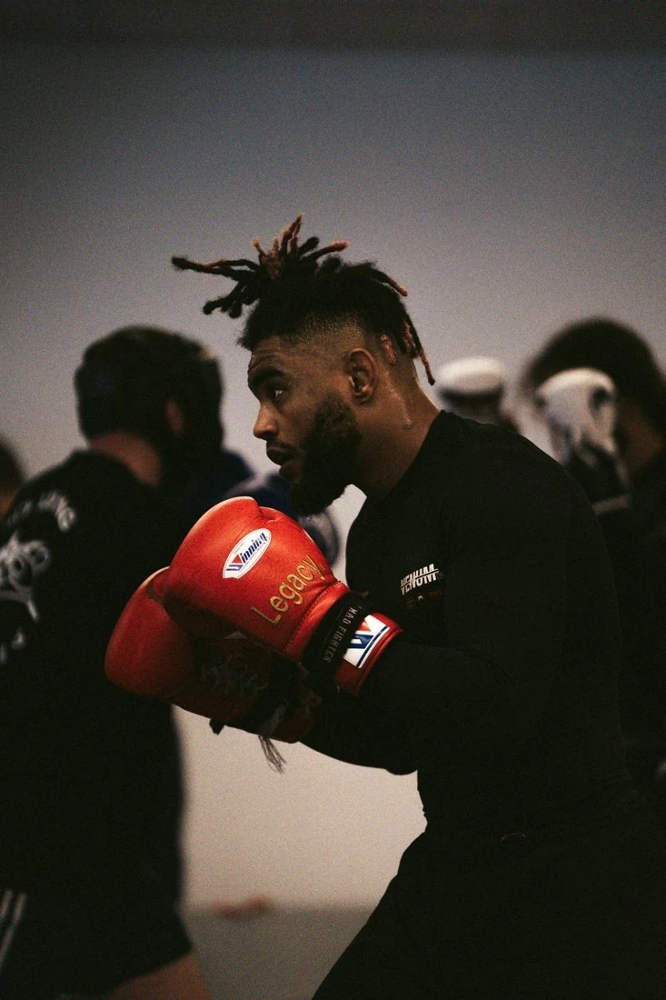 Un athlète en garde, gants de boxe rouges, pendant un entraînement.